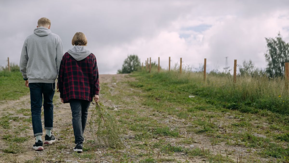 Two friends walking along a rural path in nature, enjoying the outdoors.